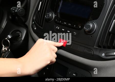 Weibliche Hand drückt Notwarntaste an der Autokonsole, Nahaufnahme Stockfoto