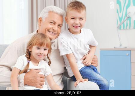 Großvater mit Enkelkindern auf der Couch sitzend Stockfoto
