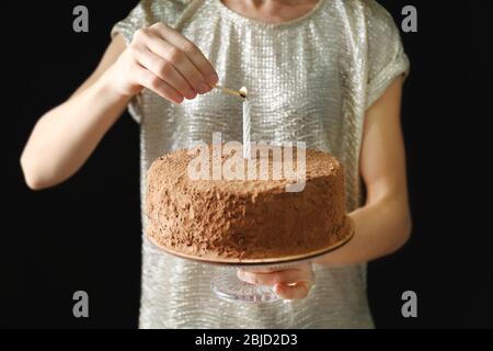 Frau licht Kerze auf Schokolade Kuchen Stockfoto