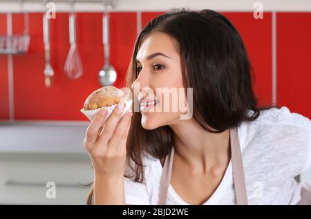 Hübsche junge Frau mit leckeren Muffin in der Küche Stockfoto