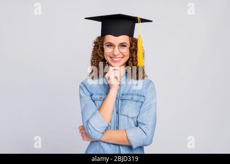 Foto von attraktiven welligen clever Dame bekam Master-Abschluss fertige Universität Quaste Kopf Finger auf Kinn tragen Spezifikationen lässig Denim blau Hemd isoliert grau Stockfoto