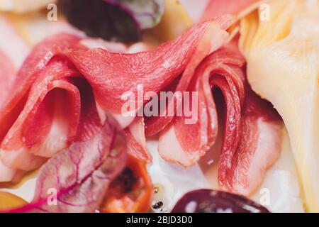 Auswahl an Vorspeisen mit Fleisch. Salami, Prosciutto, Brotstangen, Baguette, Oliven und sonnengetrocknete Tomaten, selektiver Fokus Stockfoto