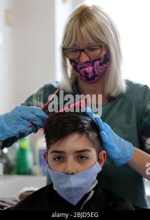 Belgrad, Serbien. April 2020. Ein Friseur, der eine schützende Gesichtsmaske und Schutzhandschuhe trägt, schneidet dem Kunden die Haare, der auch eine schützende Gesichtsmaske trägt. Die serbischen Behörden haben beschlossen, einige der restriktiven Maßnahmen zu lockern, die es einigen Unternehmen ermöglichen, ihre Geschäfte wieder zu eröffnen, um einige der Maßnahmen zu lockern, die zur Begrenzung der Ausbreitung des Coronavirus SARS-CoV-2, das die COVID-19-Krankheit verursacht, eingeführt wurden. Kredit: Koca Sulejmanovic/Alamy Live News Stockfoto