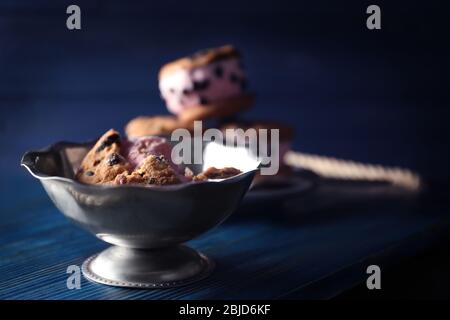 Leckere Kekse mit Eis und Schokoladenchips in Metallschüssel auf Holzbrett Stockfoto