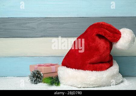 Weihnachtsmann Hut und Weihnachtsdekor auf bunten Holzhintergrund Stockfoto