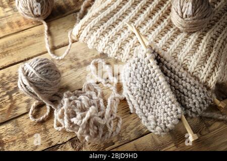 Strickgarn und Nadeln auf Holzhintergrund, Nahaufnahme Stockfoto