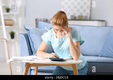 Verwirrt junge Frau Berechnung Steuern zu Hause Stockfoto