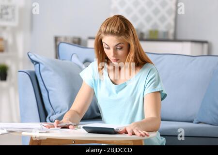 Verwirrt junge Frau Berechnung Steuern zu Hause Stockfoto