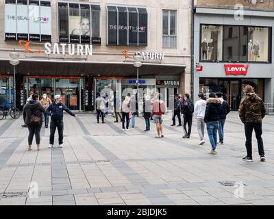 München, Bayern, Deutschland. April 2020. Dutzende von Käufern stehen an, um am ersten Tag des wirtschaftlichen Neustarts in den Saturn-Elektronikladen in München einzusteigen. Die Geschäfte in Bayern, Deutschland, werden im Rahmen der Entspannungsmaßnahmen, die alle Geschäfte auf 800 Kubikmeter begrenzen und eine Hygienedurchsetzung in den Geschäften erfordern, wie die Begrenzung der Kunden und nur maskierte Kunden in. Kredit: Sachelle Babbar/ZUMA Wire/Alamy Live News Stockfoto