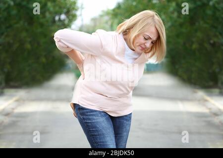 Ältere Frau, die unter Rückenschmerzen im Freien leidet Stockfoto