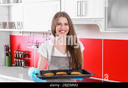 Junge Frau mit Plätzchen auf Backblech in der Küche Stockfoto