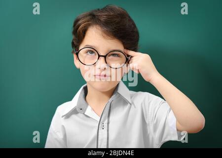 Niedlicher kleiner Junge in einer Brille auf grünem Hintergrund Stockfoto