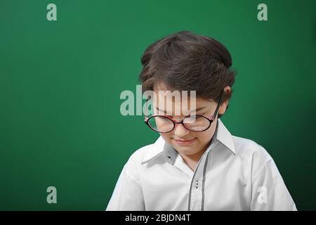 Niedlicher kleiner Junge in einer Brille auf grünem Hintergrund Stockfoto