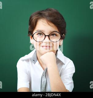 Niedlicher kleiner Junge in einer Brille auf grünem Hintergrund Stockfoto