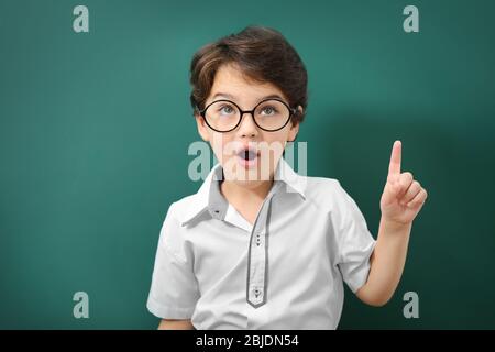 Niedlicher kleiner Junge in einer Brille auf grünem Hintergrund Stockfoto