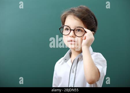 Niedlicher kleiner Junge in einer Brille auf grünem Hintergrund Stockfoto