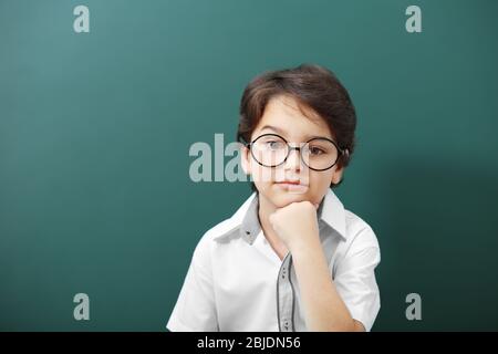 Niedlicher kleiner Junge in einer Brille auf grünem Hintergrund Stockfoto