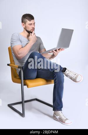 Schöner junger Programmierer mit Laptop auf farbigem Hintergrund Stockfoto