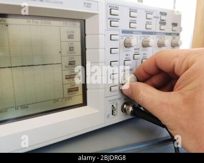 Elektroniker passt ein Oszilloskop an, um eine Frequenz zu messen Stockfoto