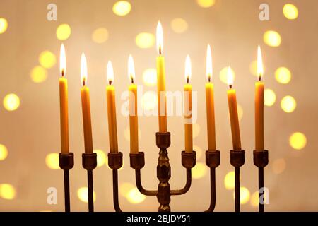 Menorah mit Kerzen für Chanukka gegen defokussierten Lichter, Nahaufnahme Stockfoto