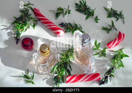 Parfümflaschen auf einer Holzoberfläche mit Karamell und Myrtenzweigen. Ätherisches Öl Stockfoto