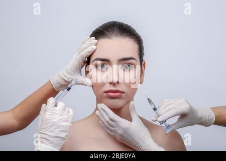 Schöne junge Frau, die Füllstoff Injektionen im Gesicht, auf hellem Hintergrund