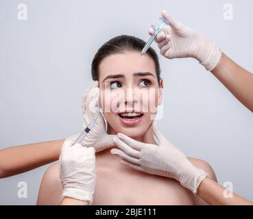 Schöne junge Frau, die Füllstoff Injektionen im Gesicht, auf hellem Hintergrund Stockfoto