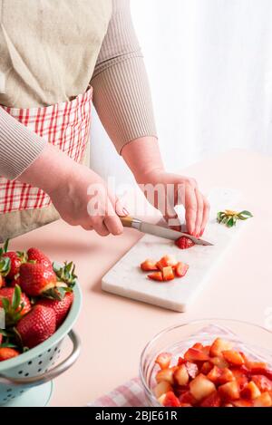 Unkenntlich Hausfrau Schneiden in kleine Stücke die Erdbeeren. Der Prozess der Herstellung Erdbeermarmelade zu Hause mit Bio-Früchten. Frau bereitet t Stockfoto