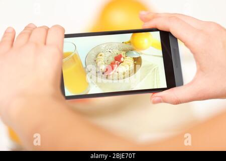 Weibliche Hände fotografieren Lebensmittel mit dem Handy Stockfoto