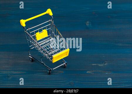 Spielzeug-Einkaufswagen auf blauem Holzhintergrund Stockfoto