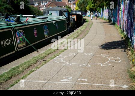 London April 2020 die Covid-19-Pandemie. Regents Canal am Victoria Park. Kreidezeichnung des Covid-19 Virus, um die Menschen an soziale Distanz und Th zu erinnern Stockfoto