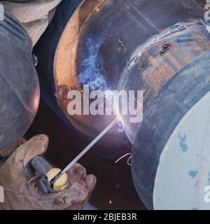 Schweißarbeiter schweißen neues Metallrohr. Stockfoto