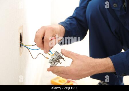 Elektriker, der Kabel an der Steckdose im neuen Gebäude ansteckt, Nahaufnahme Stockfoto