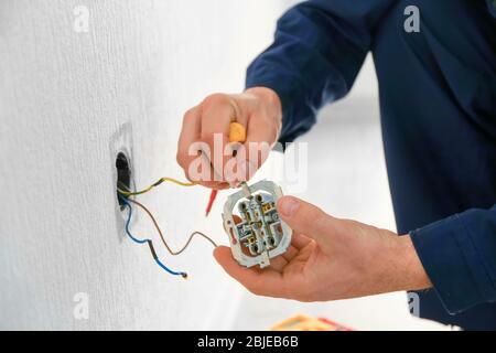 Elektriker, der Kabel an der Steckdose im neuen Gebäude ansteckt, Nahaufnahme Stockfoto