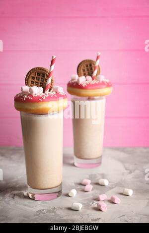 Milchshake, Donuts und andere Süßigkeiten in Gläsern auf dem Tisch Stockfoto