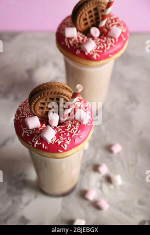 Milchshake, Donuts und andere Süßigkeiten in Gläsern auf dem Tisch Stockfoto