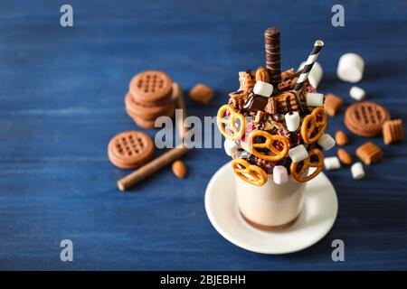 Milchshake, Donuts und andere Süßigkeiten in Glas auf blauem Holztisch Stockfoto