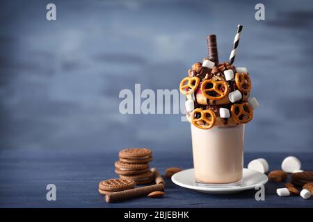Milchshake, Donuts und andere Süßigkeiten in Glas auf blauem Holztisch Stockfoto