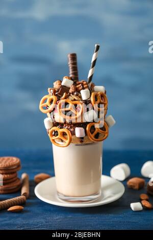 Milchshake, Donuts und andere Süßigkeiten in Glas auf blauem Holztisch Stockfoto
