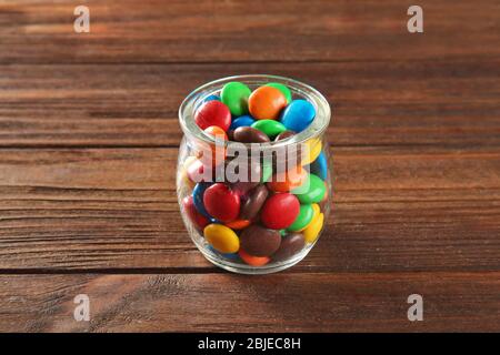 Bunte Süßigkeiten im Glas auf Holzhintergrund Stockfoto