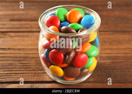 Bunte Süßigkeiten im Glas auf Holzhintergrund Stockfoto