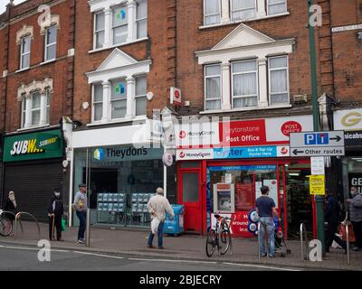 Leytonstone, London. GROSSBRITANNIEN. April 2020 um 10:30 Uhr. Foto von Leuten, die während der Sperrung am Eingang des Postamtes Schlange stehen. Stockfoto