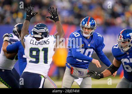 15. Dezember 2013: New York Giants Quarterback Eli Manning (10) wirft einen Pass aus dem verteidigenden Seattle Seahawks Defensive End Chris Clemons (91) Dur Stockfoto