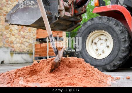 Baustelle Hintergrund mit Schaufel auf Sandhaufen und Bagger im Hintergrund. Stockfoto