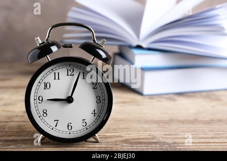 Wecker und Stapel von Büchern auf Holztisch Stockfoto