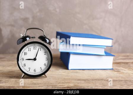 Wecker und Stapel von Büchern auf Holztisch Stockfoto