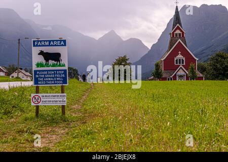 Ein Schild in der Nähe einer modernen Stabkirche bittet um Überlegungen zur Landwirtschaft in Olden bei Stryn, Norwegen Stockfoto