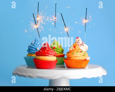 Cupcakes mit Glitzern auf farbigem Hintergrund Stockfoto