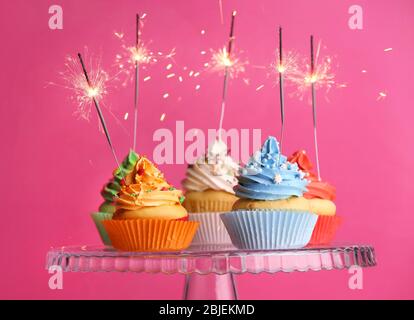 Cupcakes mit Glitzern auf farbigem Hintergrund Stockfoto