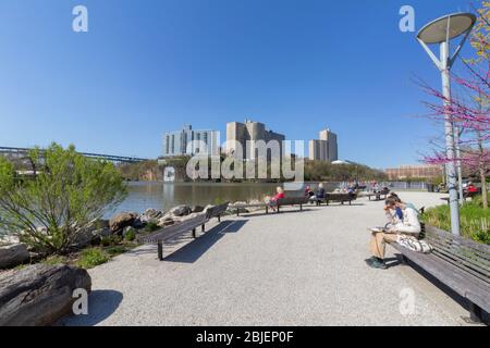 Die Leute genießen einen sonnigen Tag während der Pandemie im Muscota Marsh Park am Harlem River. Blick in Richtung Bronx Stockfoto